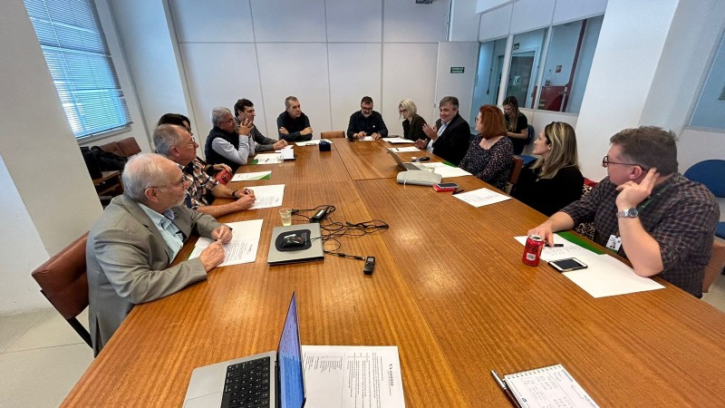 Sala de reuniões com os membros do conselho sentados em volta da mesa.