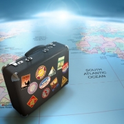 Uma maleta cheia de adesivos de vistos de companhias aéreas colocada sobre o mapa-múndi